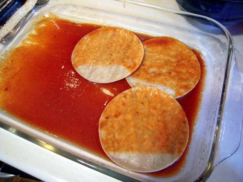 start by layering sauce soaked corn tortillas at bottom of baking dish